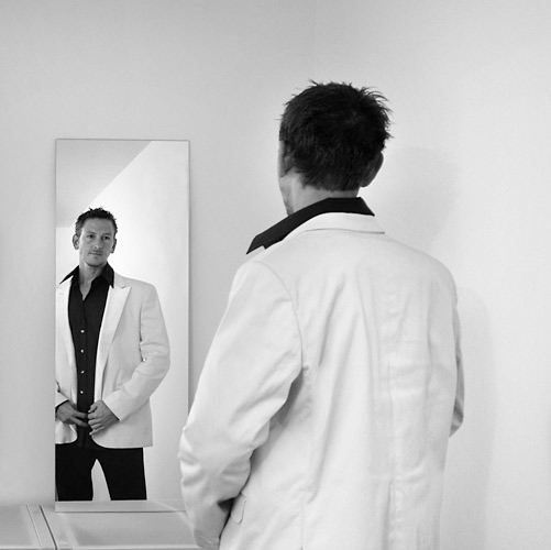 01_041 An interestingly complex portrait: mirrors are great for adding extra depth – and a touch of mystery – to a composition. Here I bounced flash off the wall behind me: this increases the apparent depth and draws the viewer towards the bright highlight behind the mirror image of the groom. ISO 400 f/4 at 1/125th