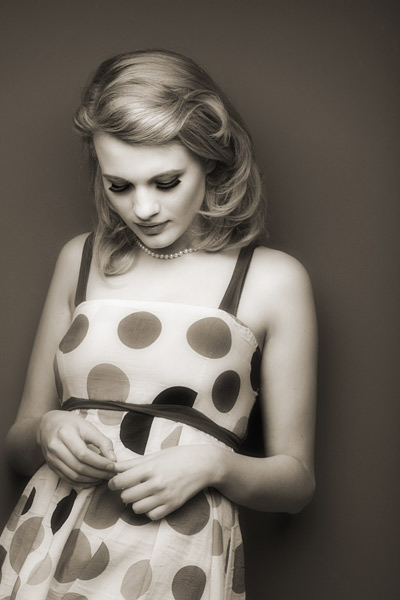 100mm lens at f/11 Next we were on to using single soft boxes to create pools of light. The technique used here is to set the light up horizontally hanging from the overhead rails as if it is over a snooker table. The light is not directly above Chloe it is in front of her. It is at 90 degrees to the wall and this helps to keep the tonal separation effortless. This is one of my favorite shots of the set. I asked Luke, one of our picture editors to come up with a vintage post production look that used a lift in the shadows together with a non linear tint. The next two pictures use the same Photoshop action.